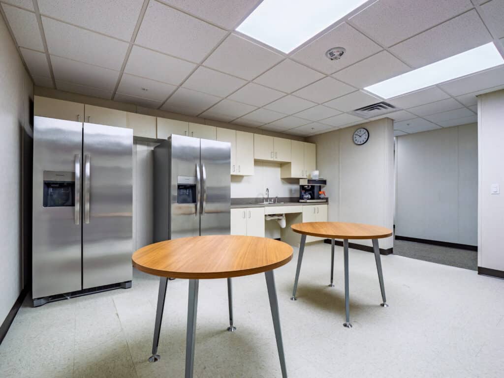 Break room with full kitchen, two refrigerators and tables in the modular office building