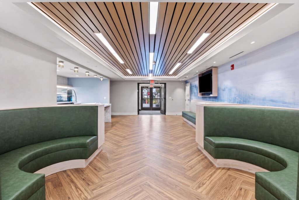 Training cafe with green banquette seating, serving counter and wood-slat ceiling in the permanent modular school building