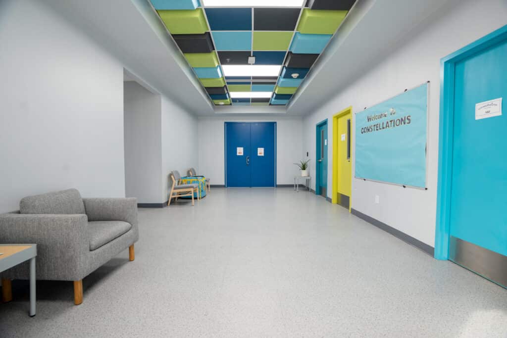Corridor with a Welcome to Constellations banner, soft seating and coloured ceiling baffles