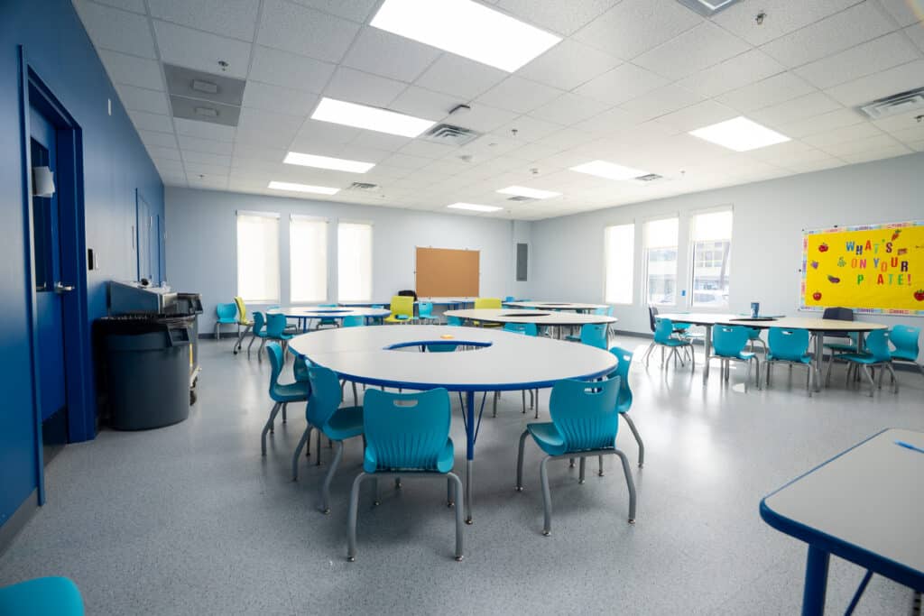 Classroom with a round table, individual desks and daylight from three windows in the modular school building