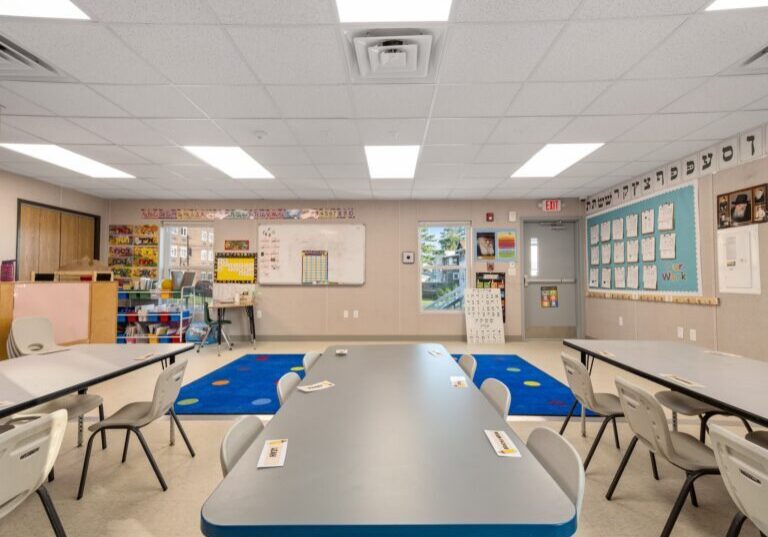 Classroom with tables, chairs, and educational materials on the walls.