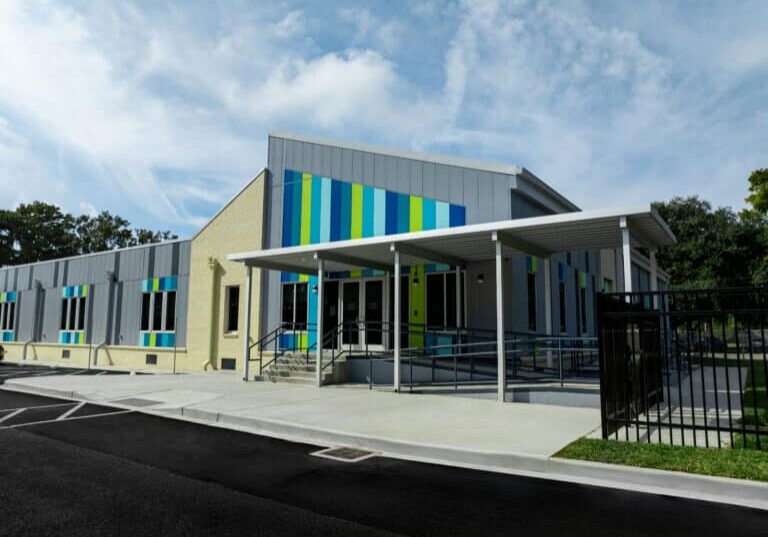 Crescent School, Front of the building outside. Permanent modular school building for the Constellations program in New Orleans, with grey and cream panelled facade and coloured window accents