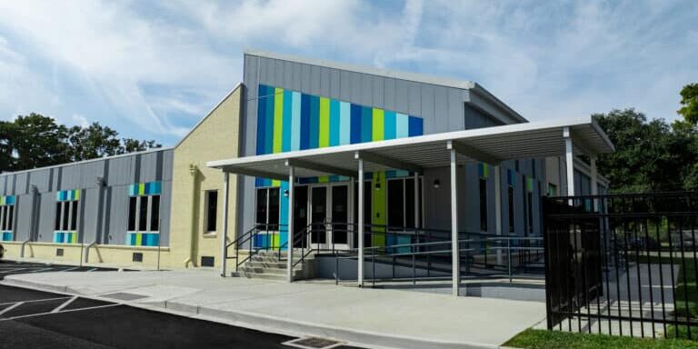 Crescent School, Front of the building outside. Permanent modular school building for the Constellations program in New Orleans, with grey and cream panelled facade and coloured window accents