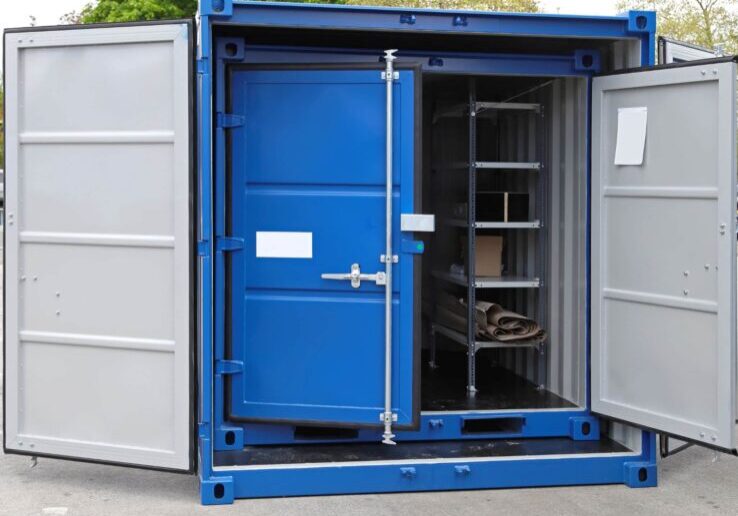 Blue steel storage container with doors open, revealing shelving and stored items inside, set outdoors with trees in the background.
